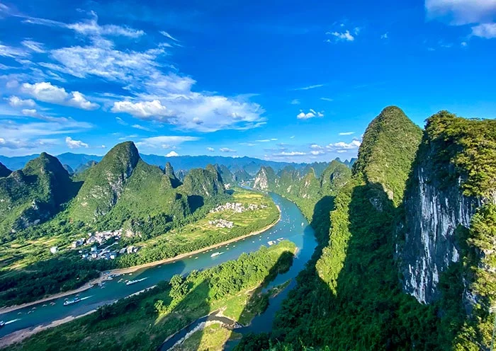 Aerial view of the Li River winding through lush green karst peaks under a blue summer sky