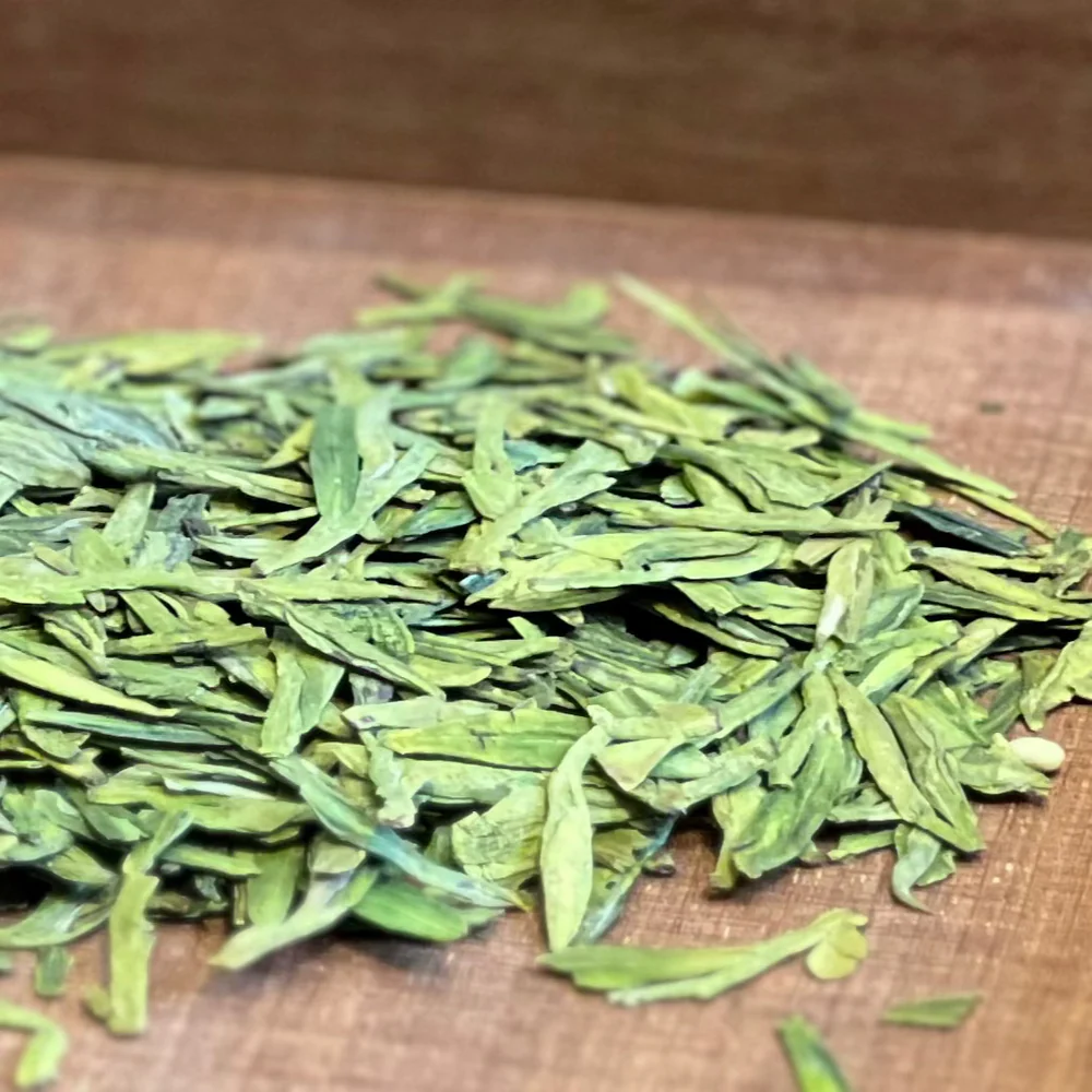 Longjing green tea in a clear glass cup showing pale jade-coloured liquor